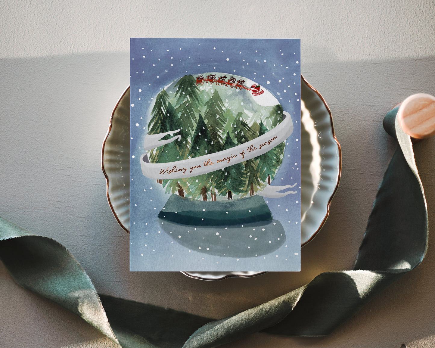 a christmas card with a snow globe on a plate