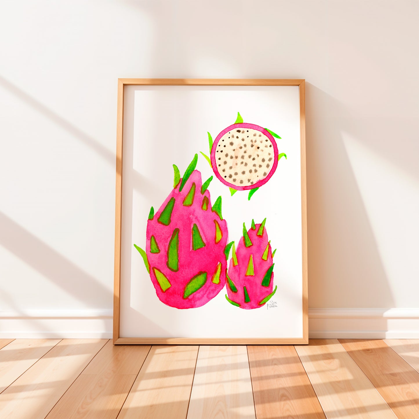a framed watercolor painting of three dragon fruits, each with a unique shape and vibrant pink color.