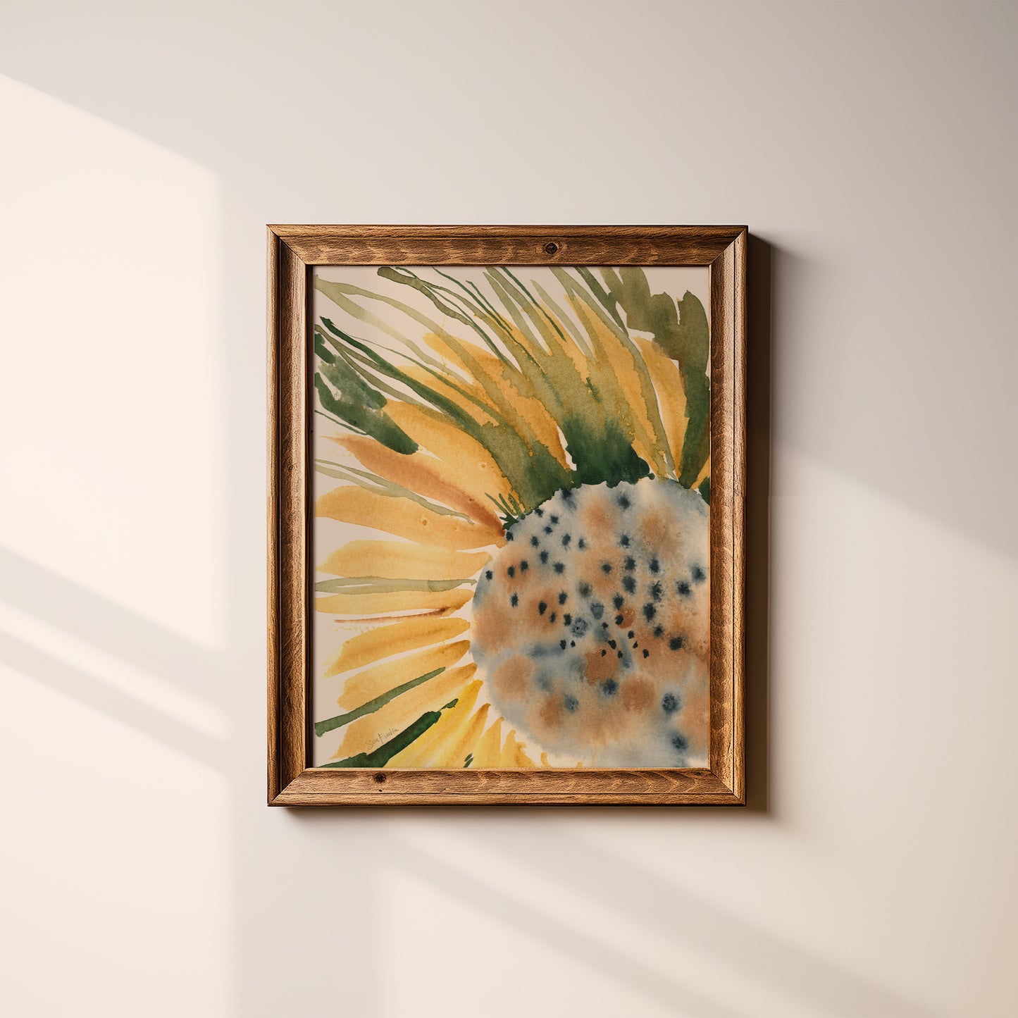 a framed watercolor painting of a sunflower on a white wall.