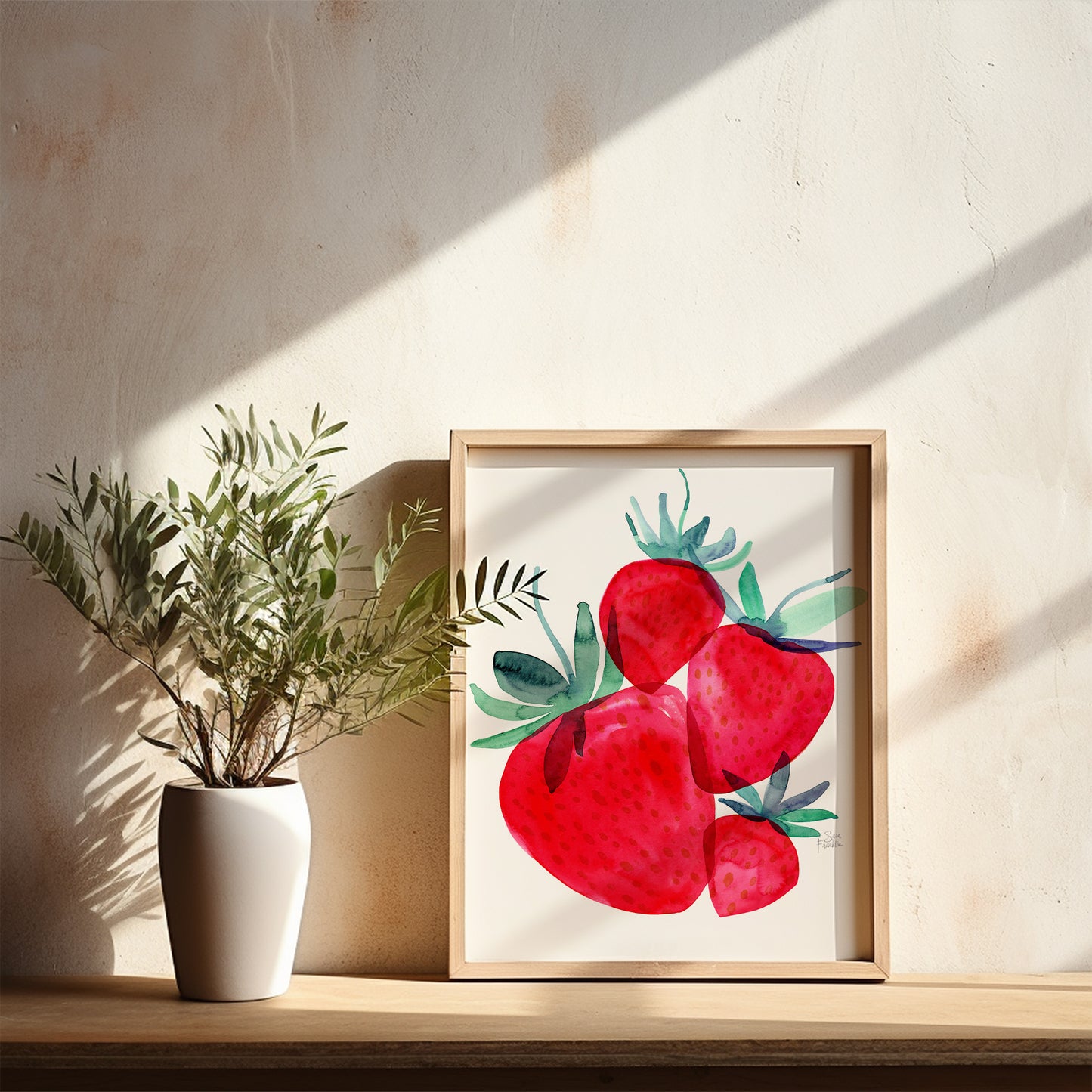 a white vase with a plant on a shelf, and a framed painting of red strawberries on a wall.