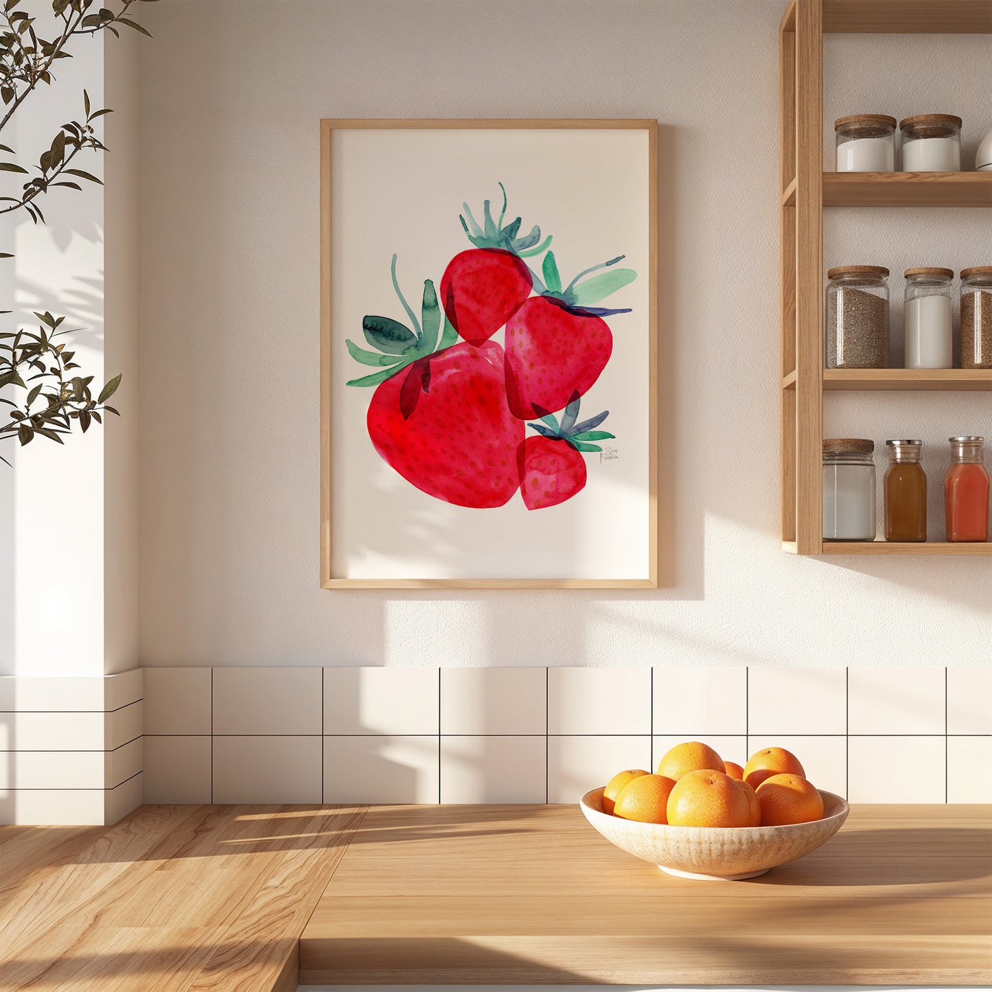 a framed painting of red strawberries hanging on a white wall above a wooden table with a bowl of oranges.