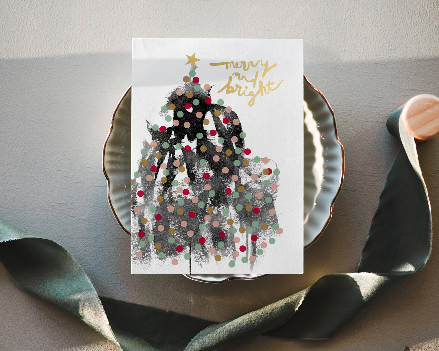 a christmas card on a plate next to a leaf