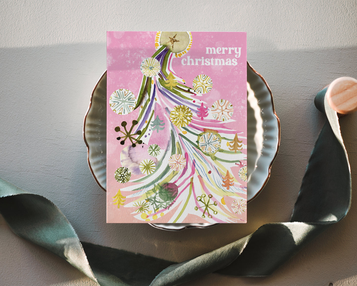 a christmas card on a plate next to a spoon