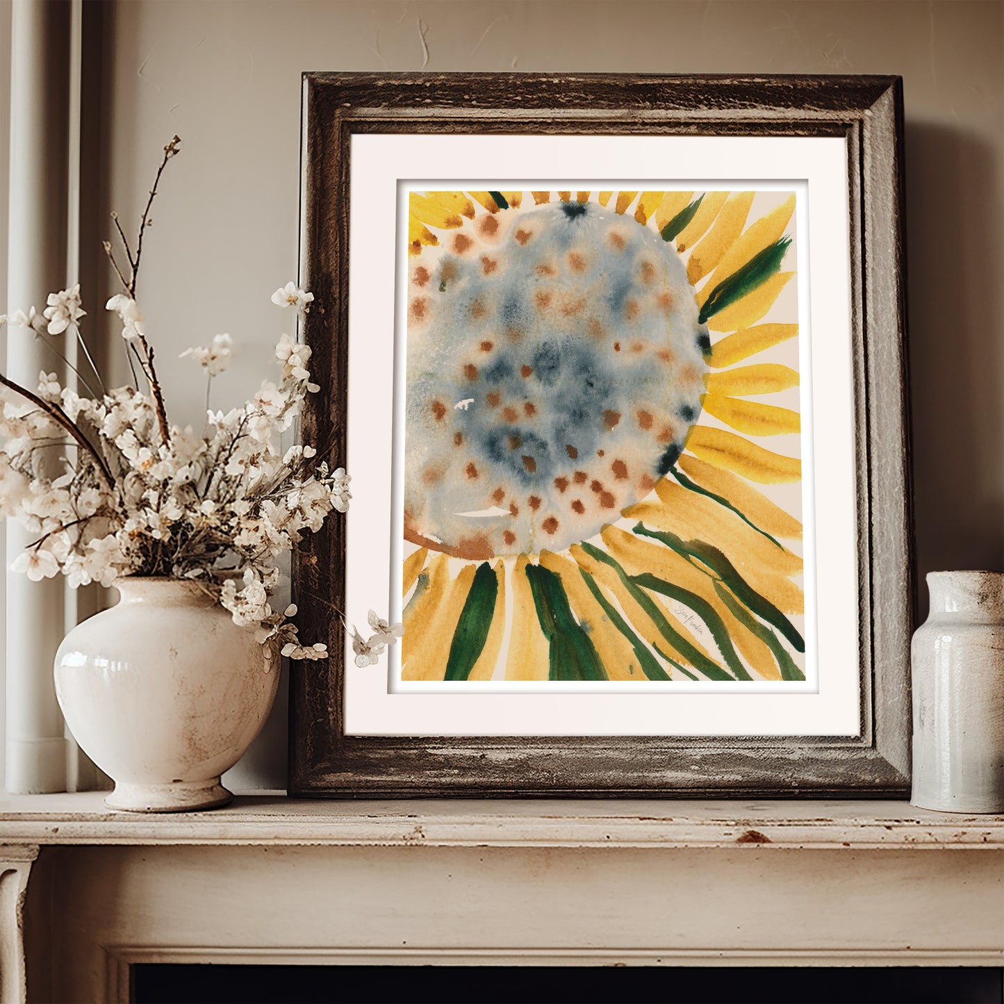 a framed watercolor painting of a sunflower, placed on a shelf next to a white vase filled with white flowers.