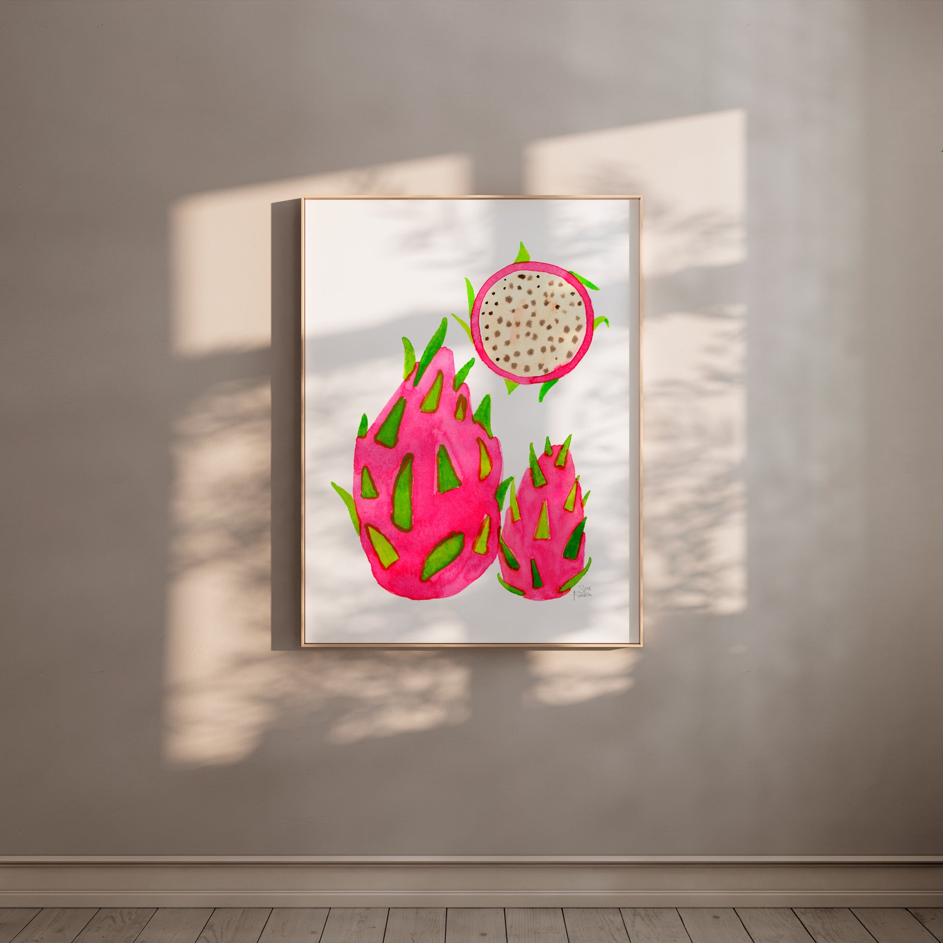 a framed artwork of three dragon fruits hanging on a wall.