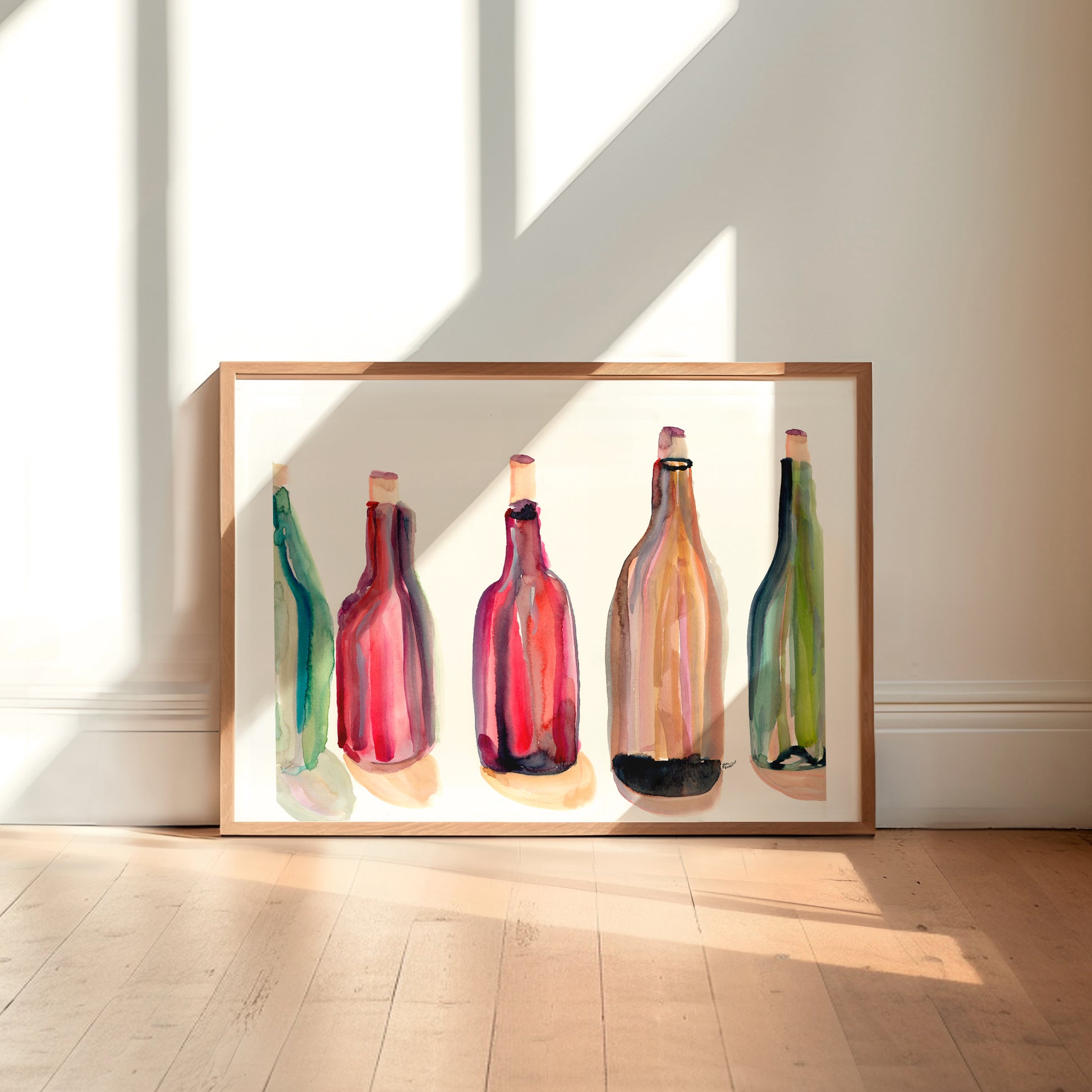 A framed painting of five colorful bottles of wine is displayed on a wooden floor against a white wall.
