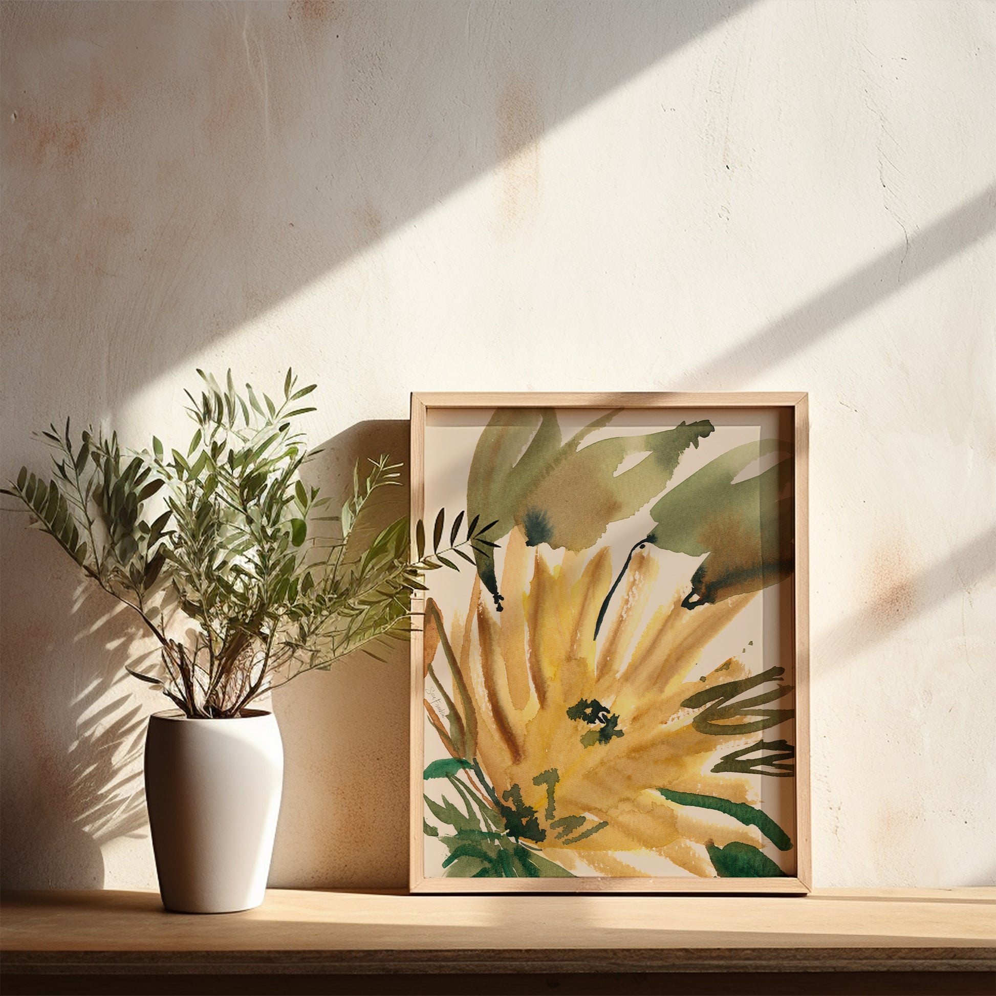 a white vase with a plant on a shelf, next to a framed painting of a yellow flower with green leaves.