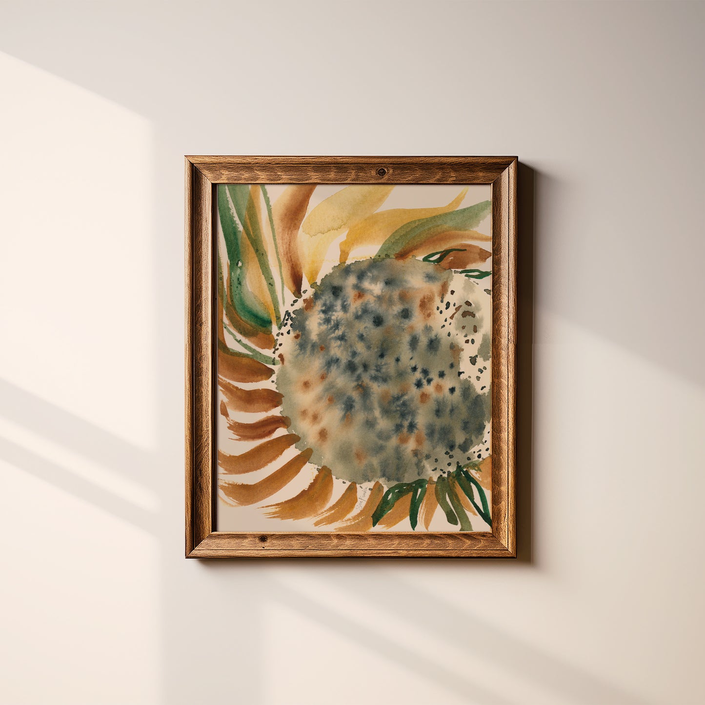 a framed watercolor painting of a sunflower on a white wall.