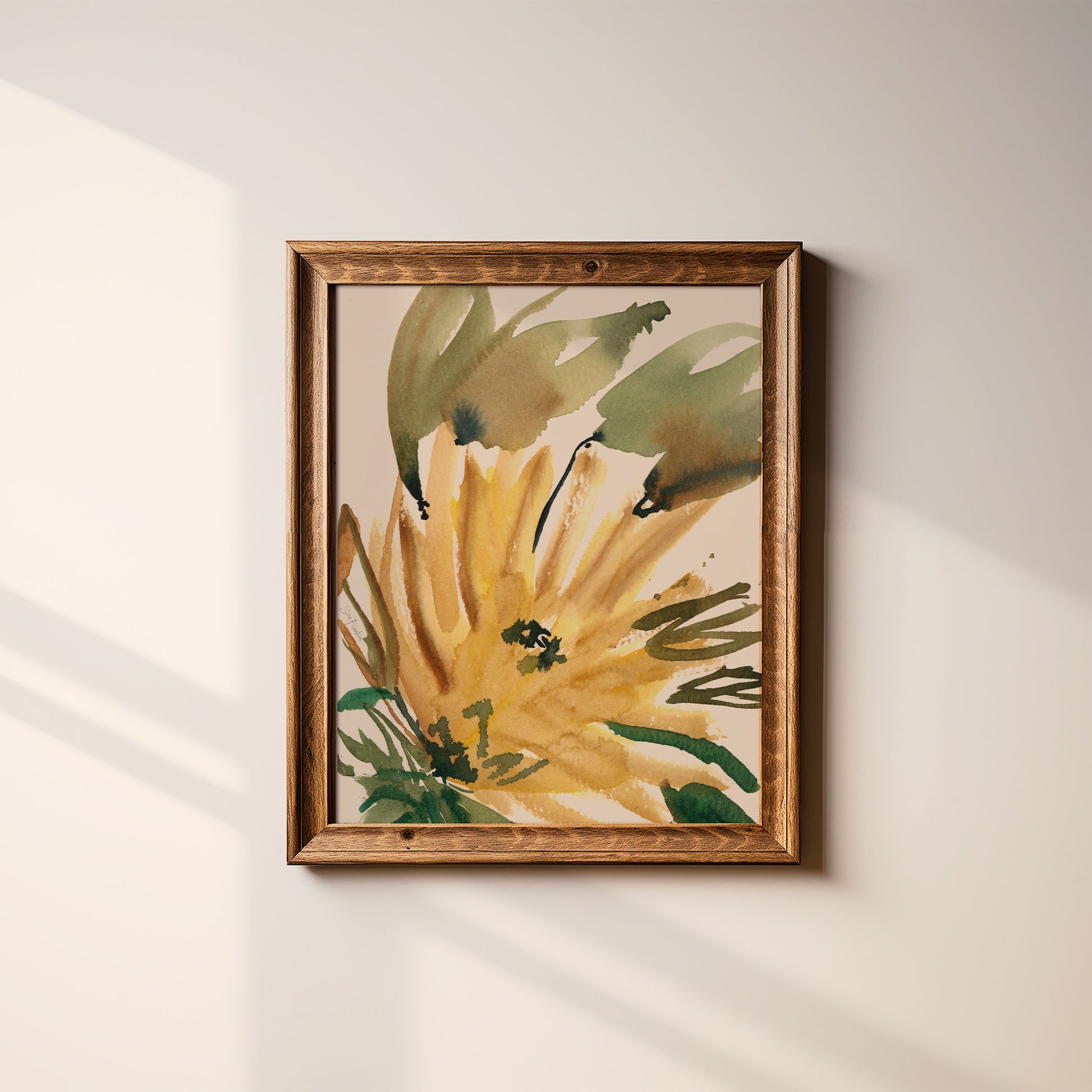 a framed painting of a yellow flower with green leaves, hanging on a white wall.