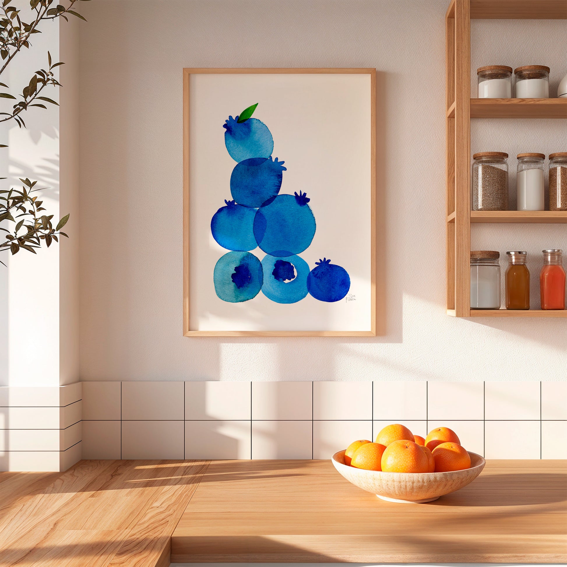 a kitchen scene with a wooden table, a bowl of oranges, and a framed artwork of blueberries on the wall.