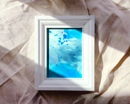 a white frame with a blue and white painting on it