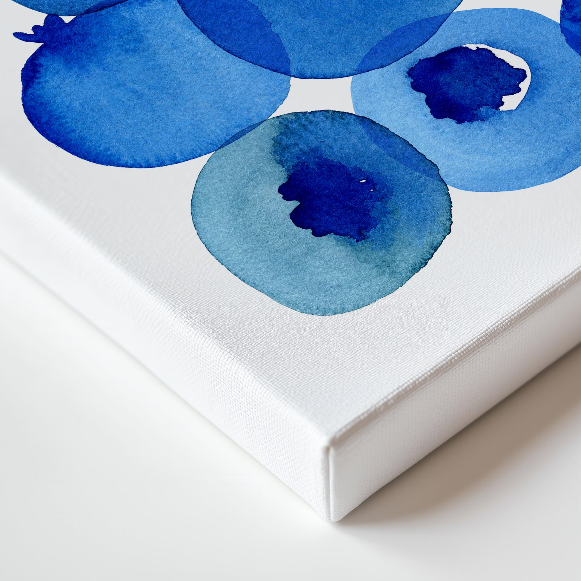 a close-up view of a white canvas with a watercolor painting of blue circles on it.
